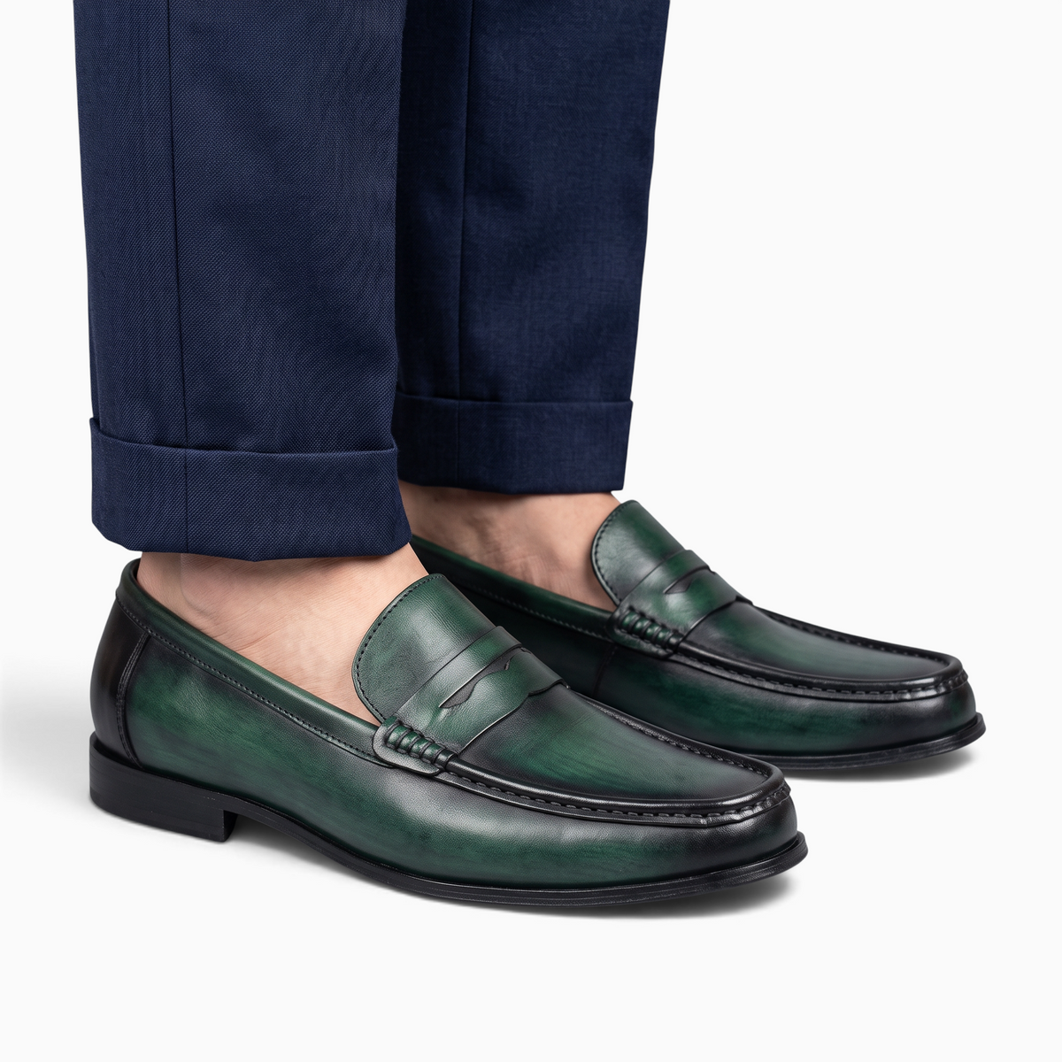 Mocassin Paris homme en cuir vert patiné avec semelle en caoutchouc, porté avec un pantalon de costume bleu marine.
