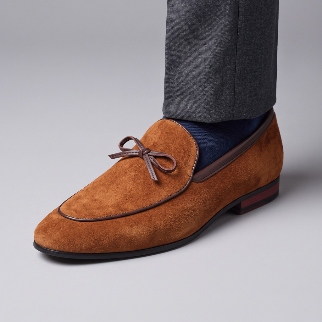 Mocassin Paris homme en daim marron avec détail de nœud, porté avec un pantalon gris pour une tenue habillée.