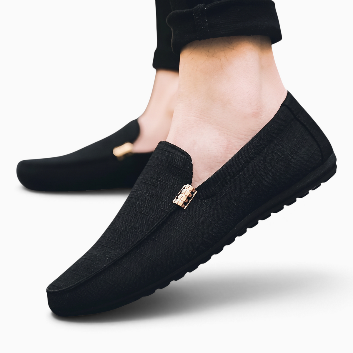 Mocassin Paris homme en tissu noir respirant avec bout rond et détail métallique, porté pour un style décontracté.