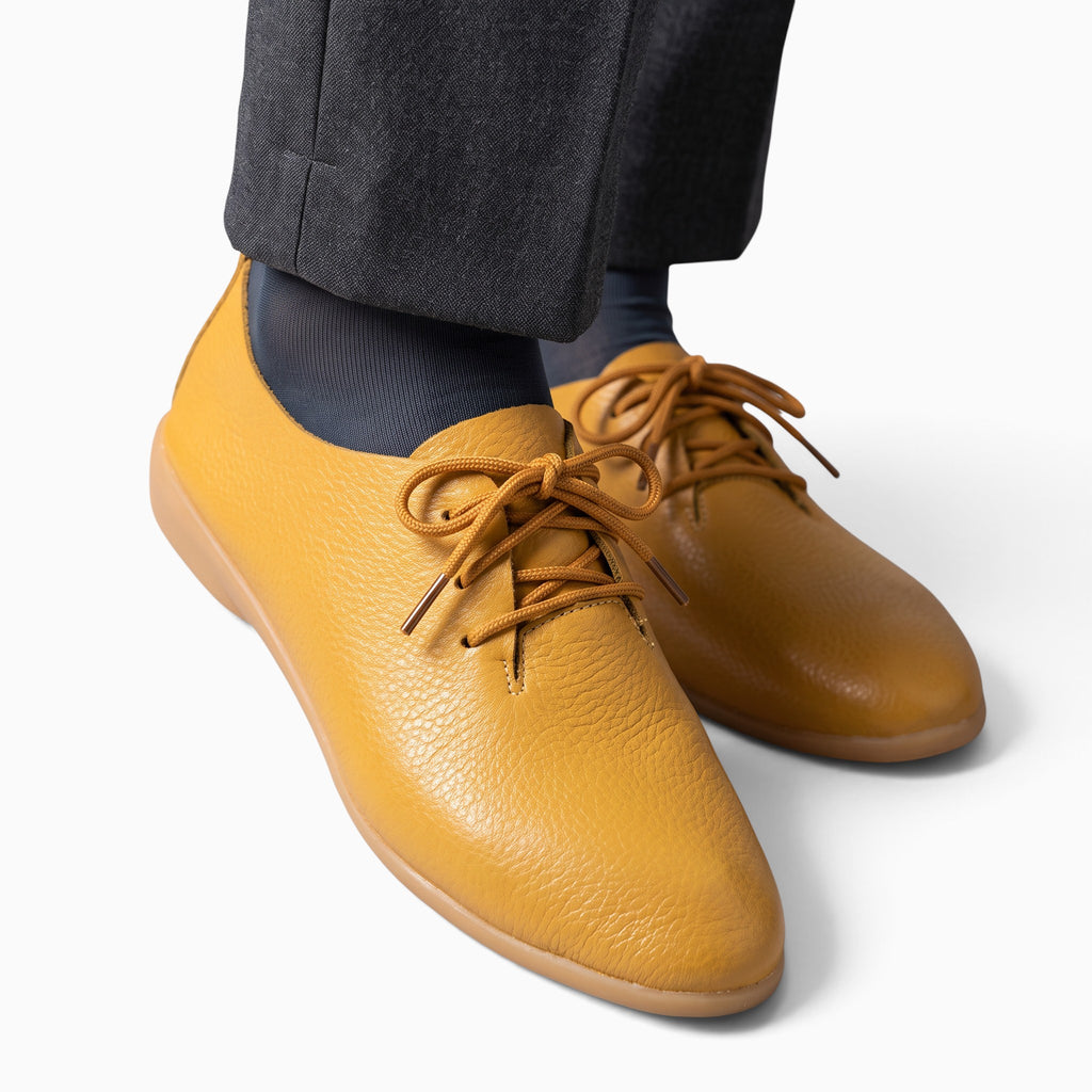 Mocassin Paris femme en cuir grainé moutarde à bout pointu et lacets, porté avec un pantalon gris